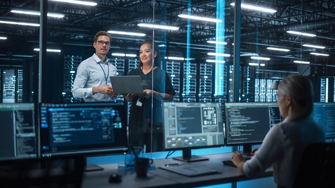 Female e-business entrepreneur and male IT specialist discussing security in a server room 