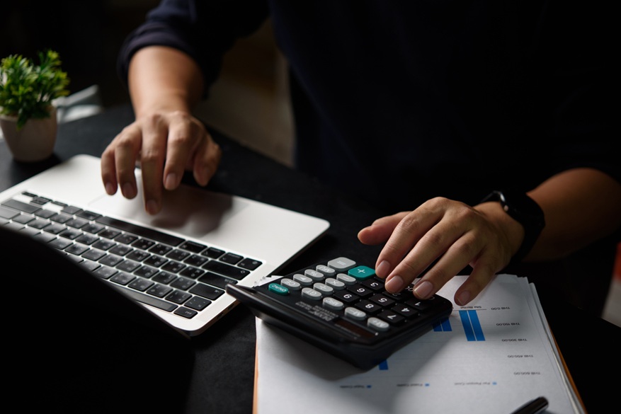 A person using a laptop and a calculator. 