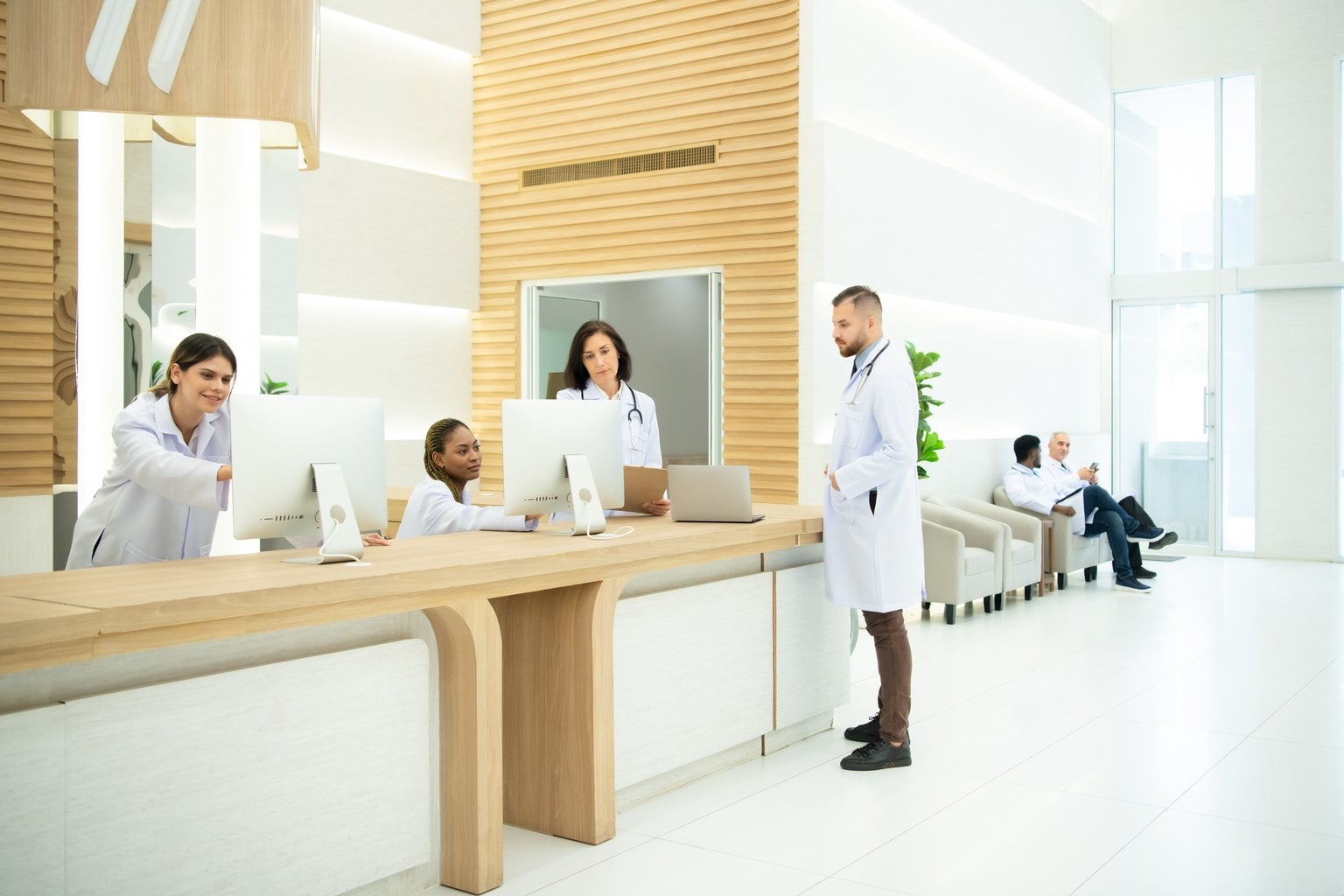 Clinical staff working at computers behind a medical practice reception desk